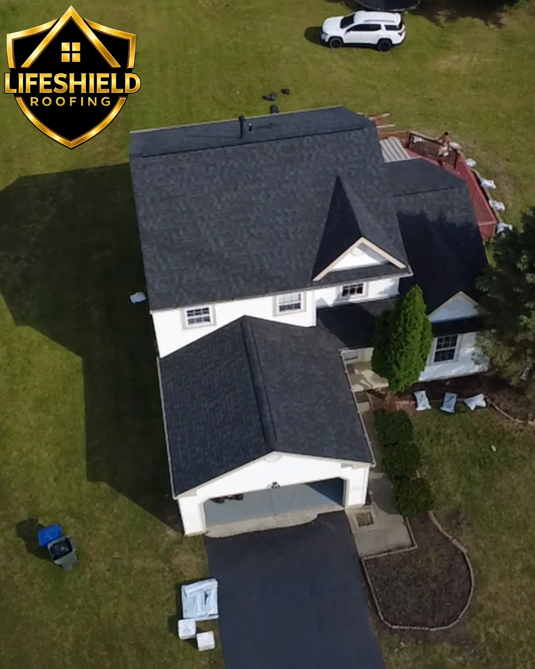 Aerial view of two-story home with new charcoal gray asphalt shingle roof installation